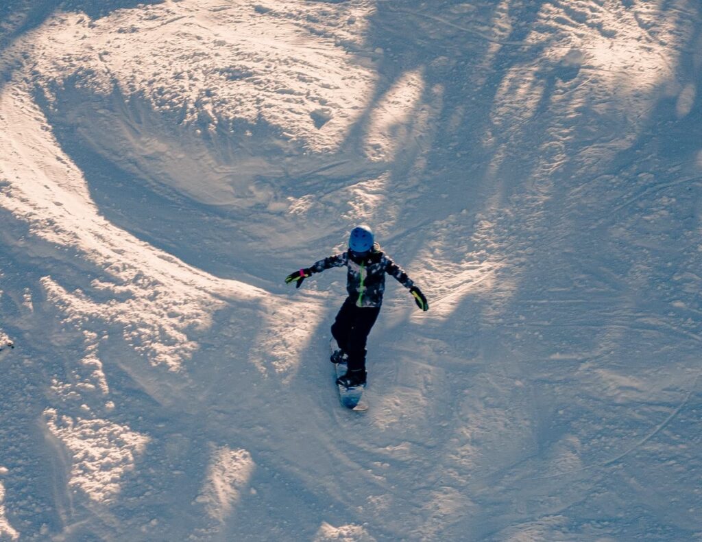 Snowboarder gliding down snowy slope wearing blue helmet
