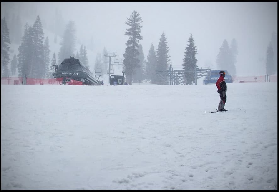 One snowboarder standing in the snow at the base of Squaw Valley during a snow storm in North Lake Tahoe