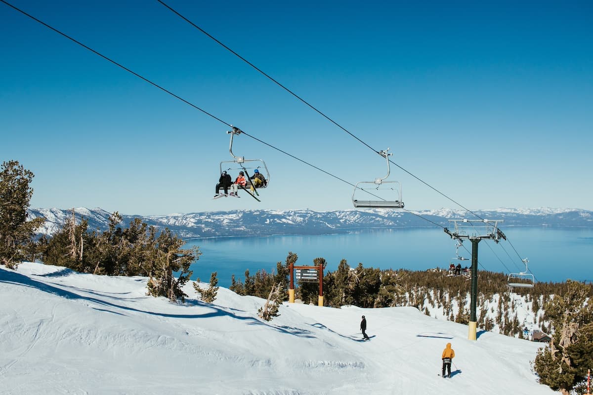 Skiiers on ski lift at Heavenly Resort Lake Tahoe with blue skies and blue lake in background