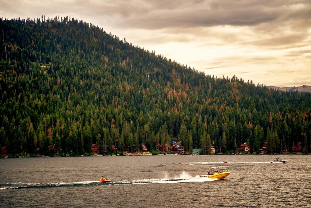 Boats in Donner Lake on a hazy day with tall green forests in background