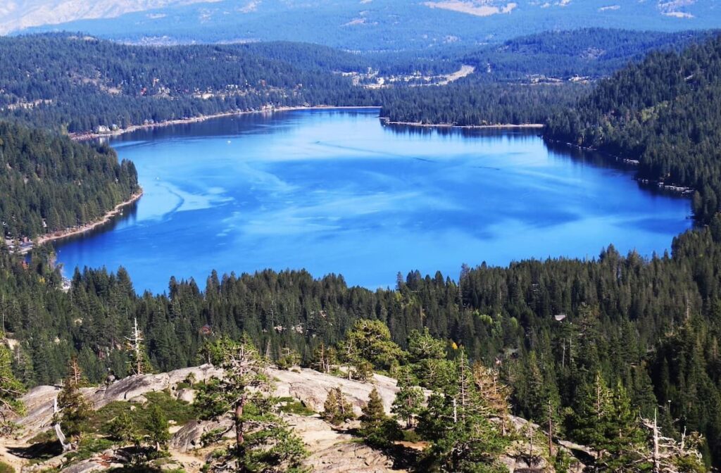 High-up view of Donner Lake with bright blue waters surrounded by green trees