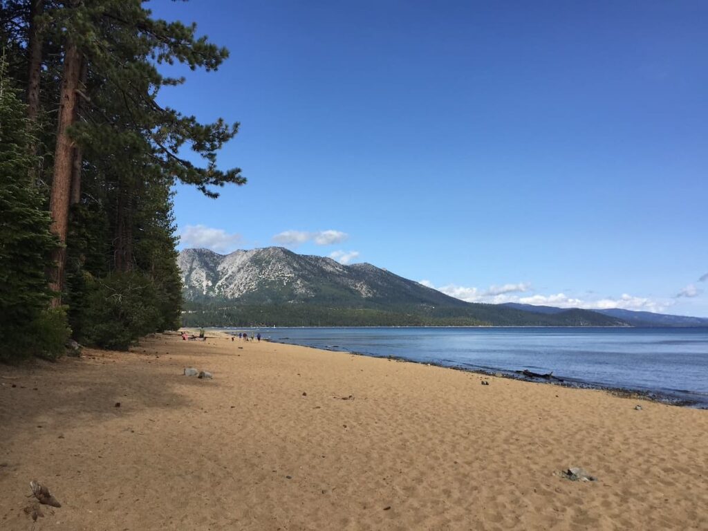 Empty beach at Kiva beach with  tall green trees beside the sand and mountain in background