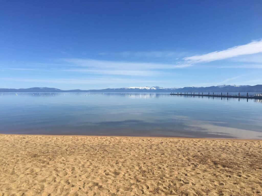 Calm blue waters at Pope Beach with snow-capped mountain in the distance