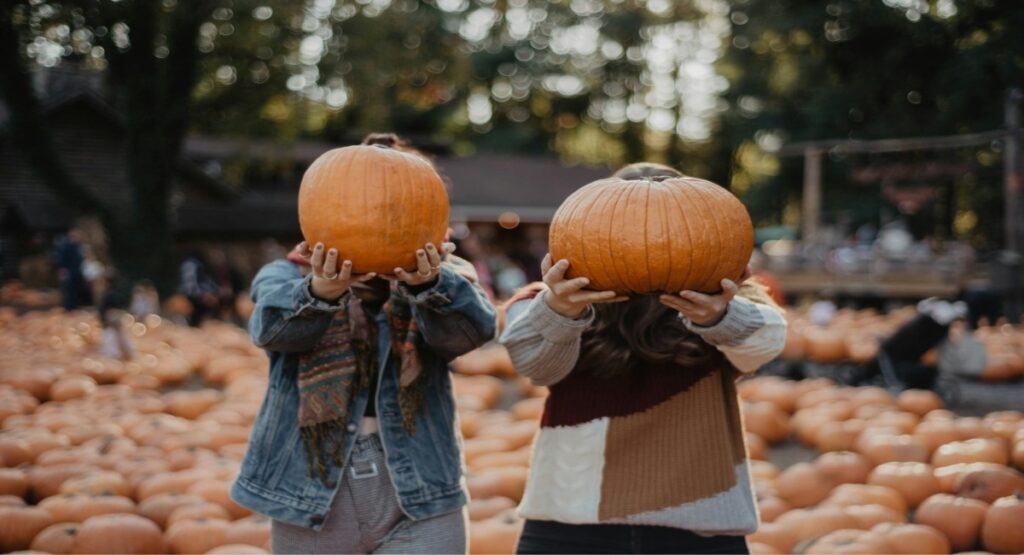 Two kids holding up pumpkins at a pumpkin patch in Gearhart