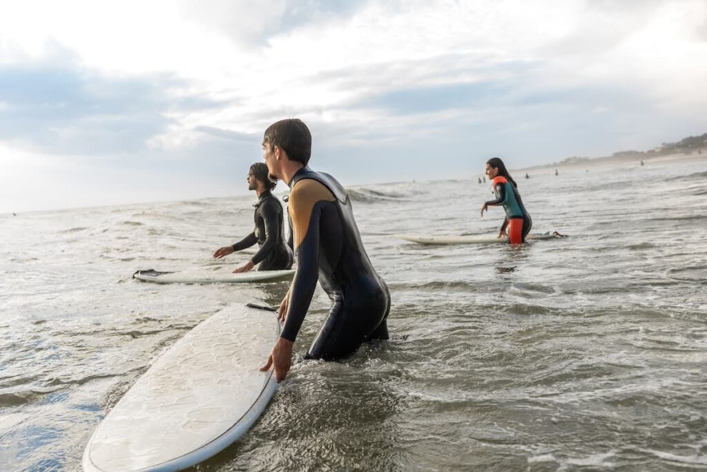 Three people in wetsuits surfing in the pacific ocean along the Oregon coast