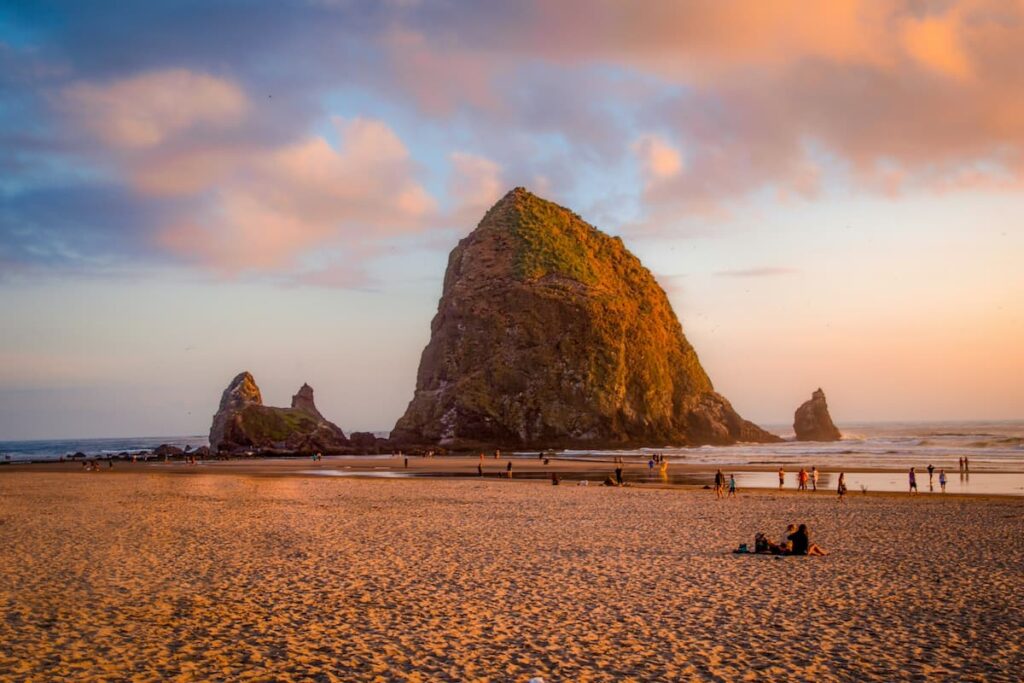 People at Cannon Beach at sunset with large Haystack Rock in background