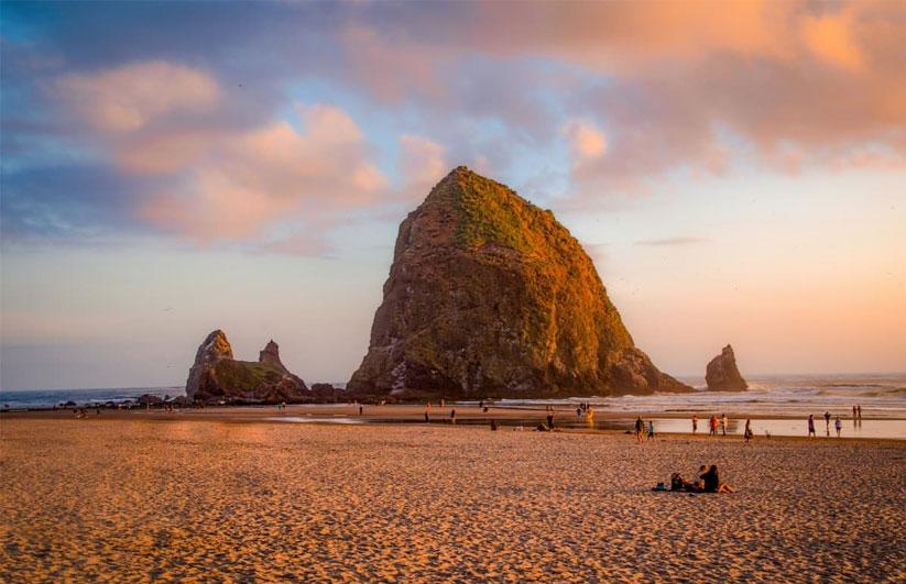 People at Cannon Beach at sunset with large Haystack Rock