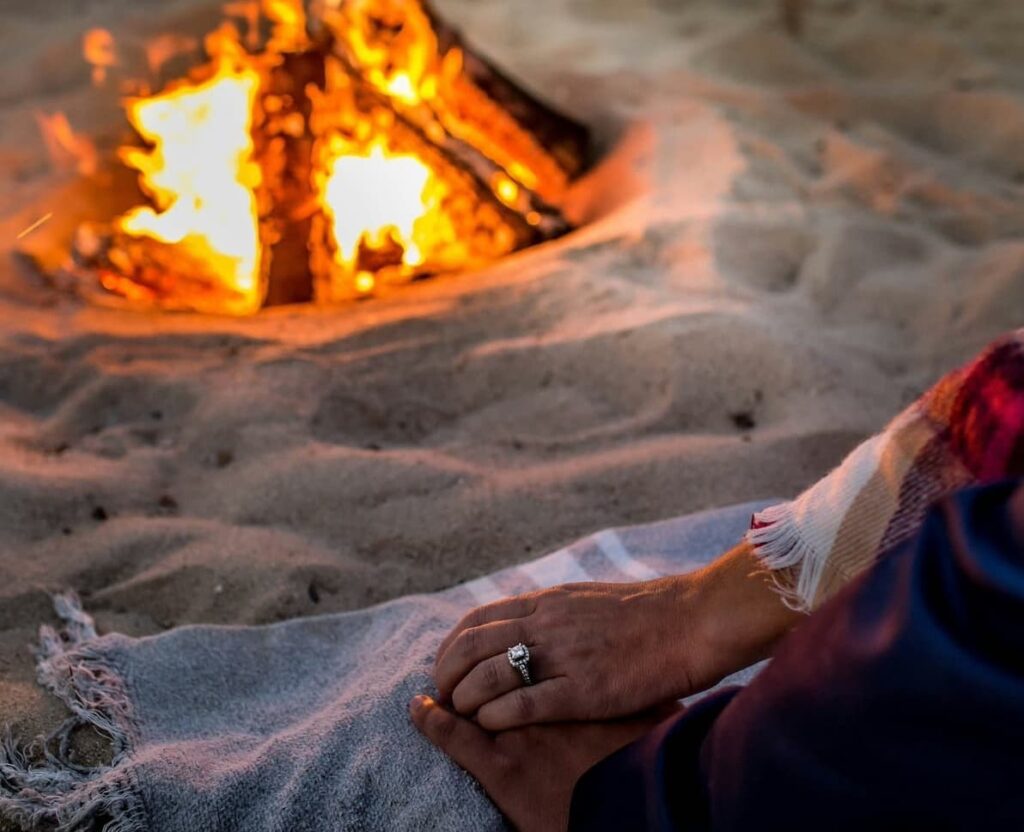 engagement on beach near woodfire