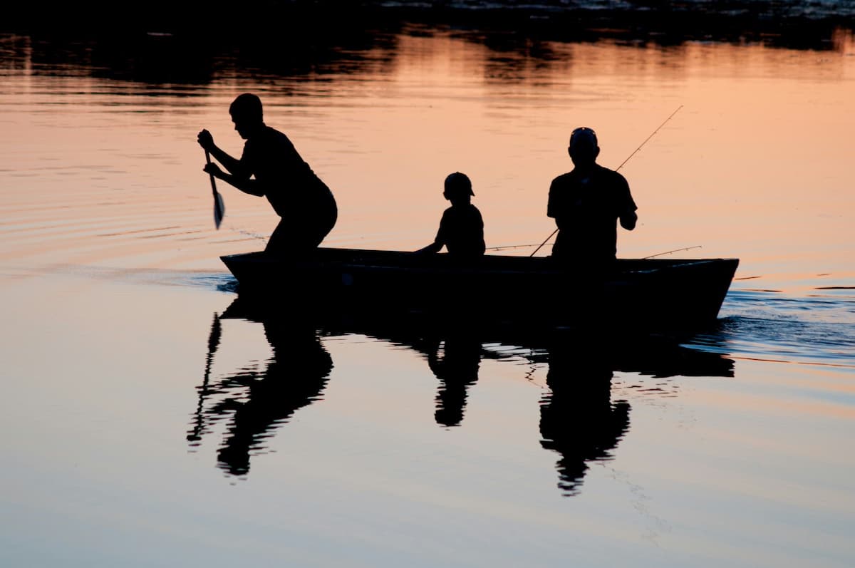 Silhouette of three people in a small boat fishing on the Oregon Coast