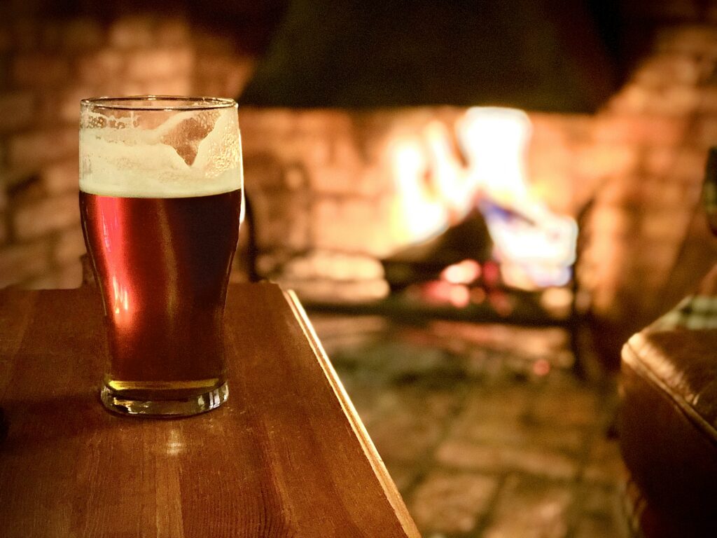 pint of beer on a table in front of an open fire - winter pub