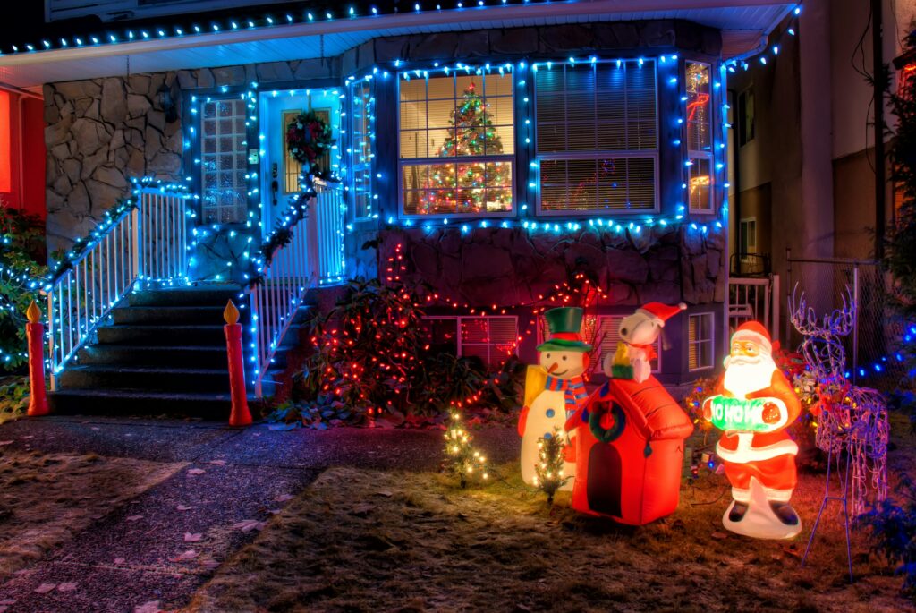 home decorated for Christmas - blue lights around the window, Christmas tree in the front room, Santa Claus and other figures on the lawn