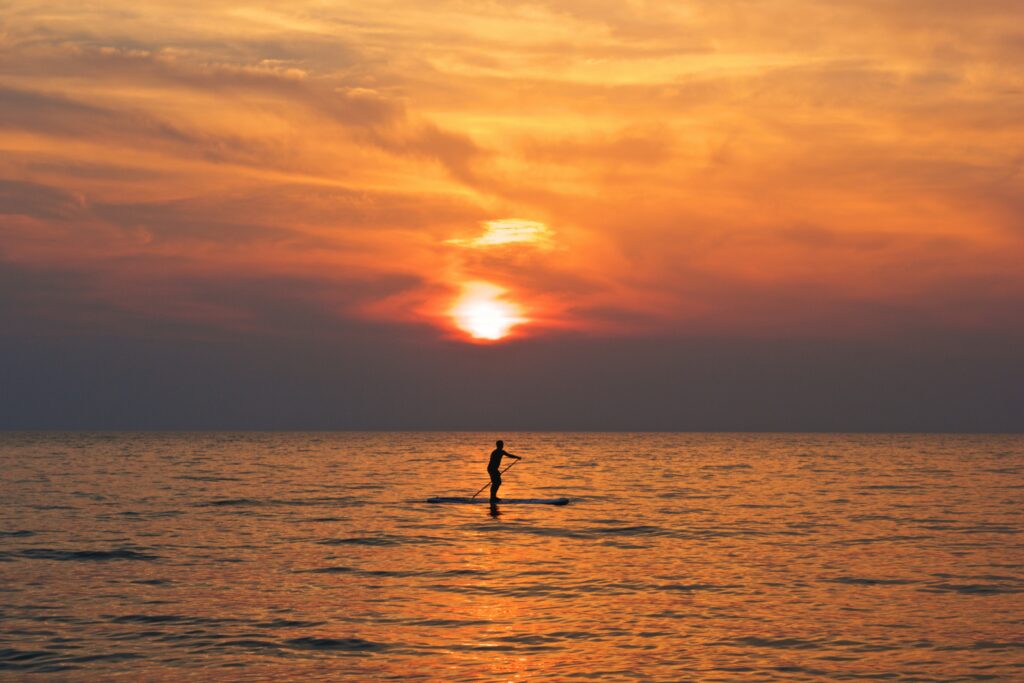 paddleboarder on the ocean during sunset