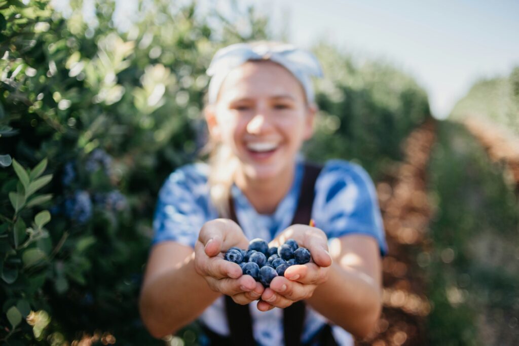 girl holding handful of blueberries on a farm
