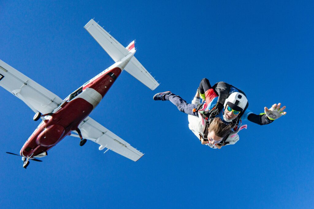 tandem skydiving from a small plane against a blue sky