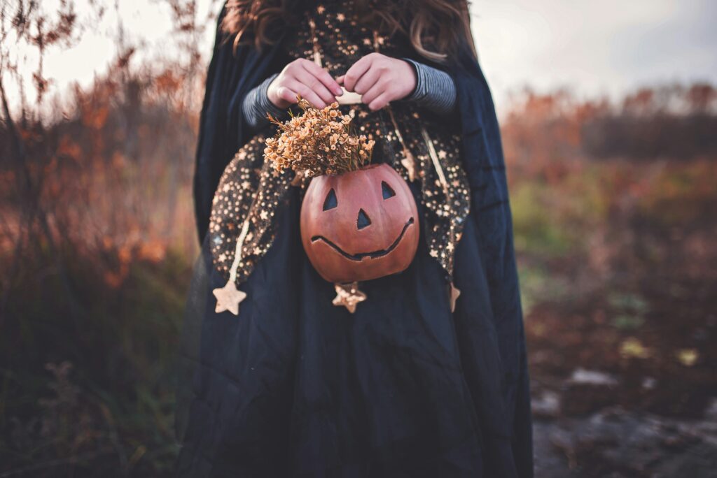 person dressed up for halloween holding a pumpkin