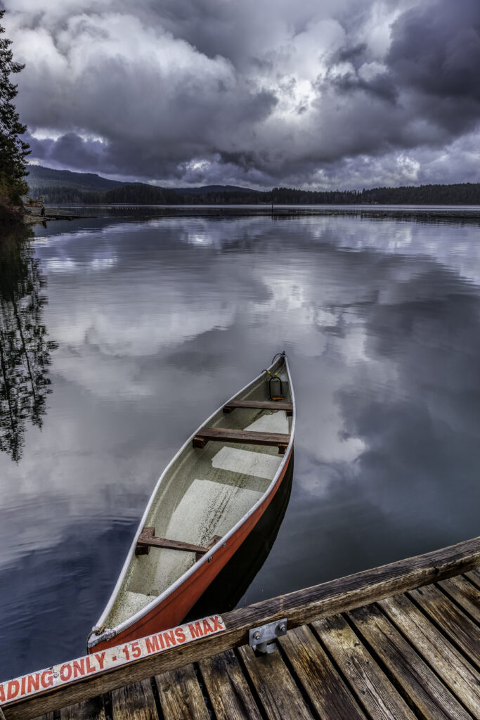 red canoe floating on Comox Lake in Comox BC cloudy skies and still water
