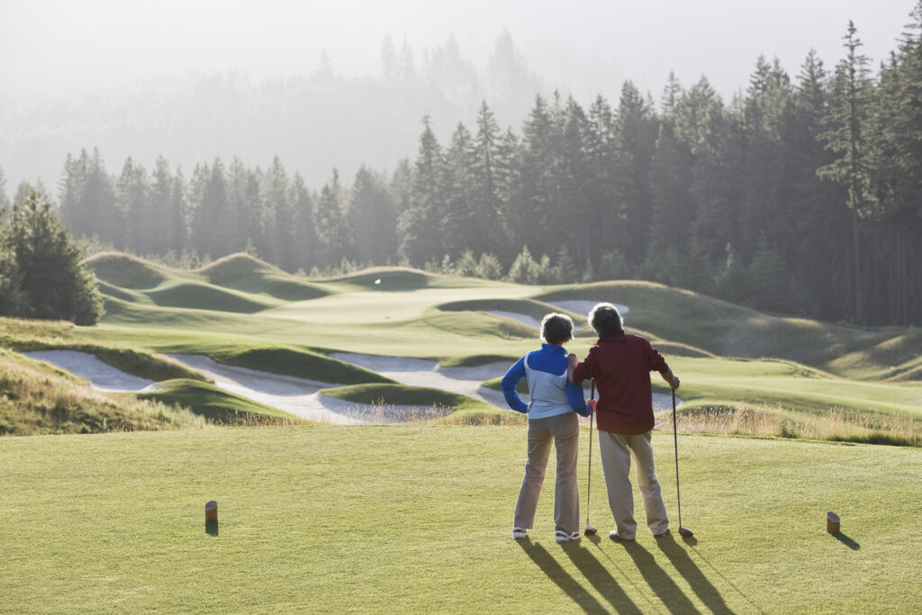 older couple on a golf course in on a cooler, sunny morning