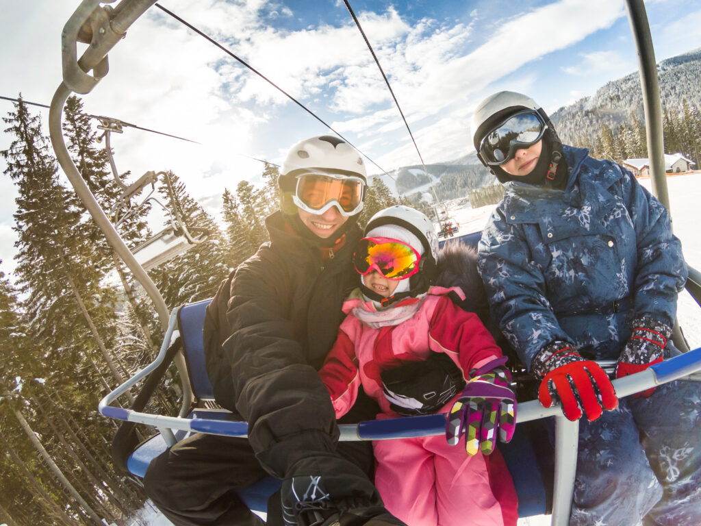 family on a ski lift taking a selfie on a sunny day on a ski trip