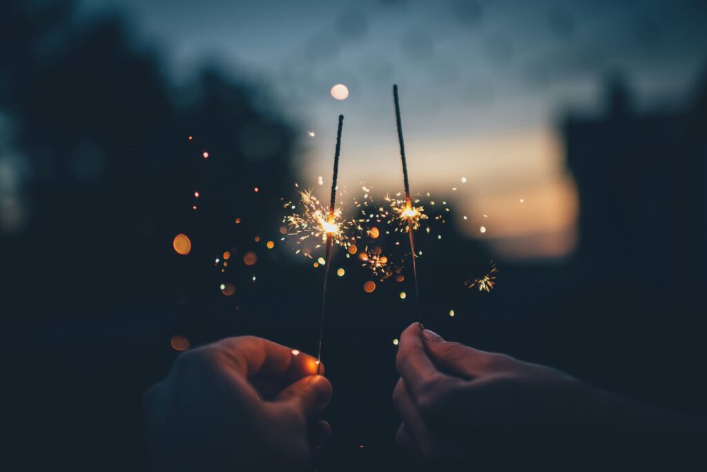 two people holding new years eve sparklers at night