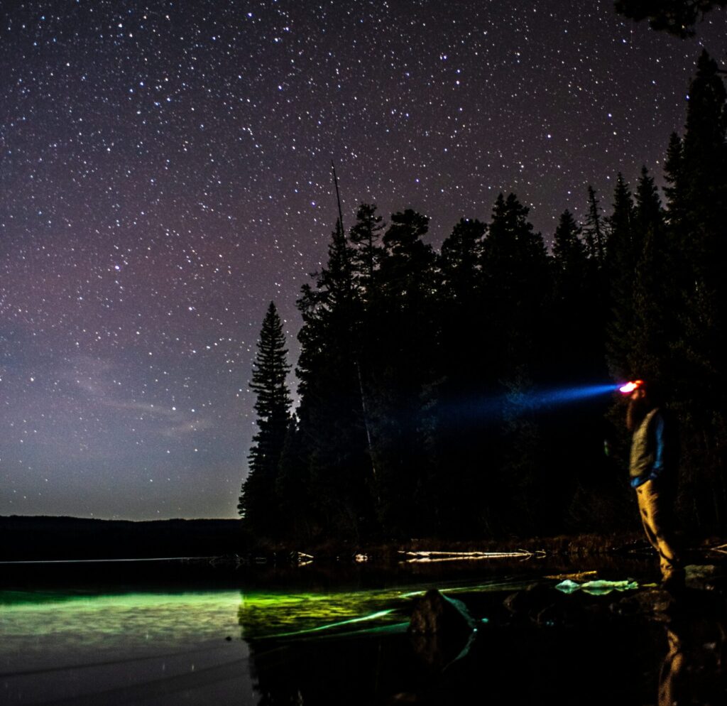 man standing on the edge of the water with bioluminescence