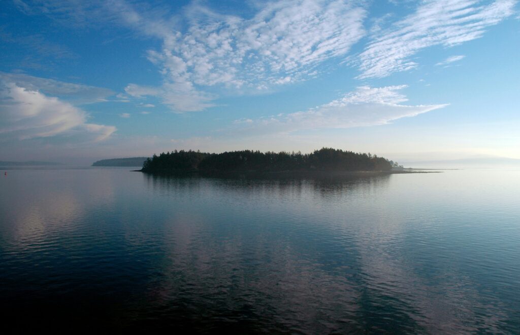 Distant Gulf Island on a sunny day - blue sky reflecting on the ocean