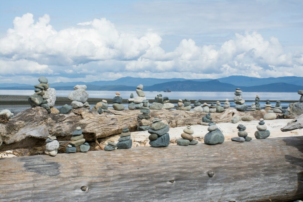 many small inukshuk on driftwood on a beach in Parksville BC